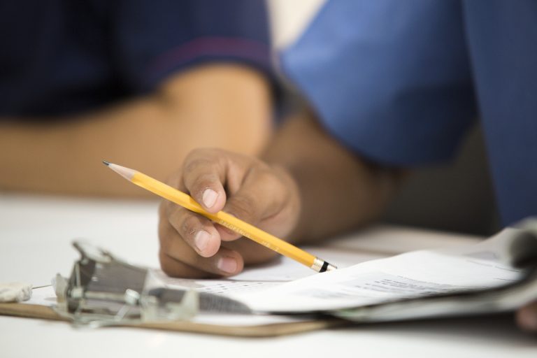 A person holding a pencil over paperwork working on data compliance.