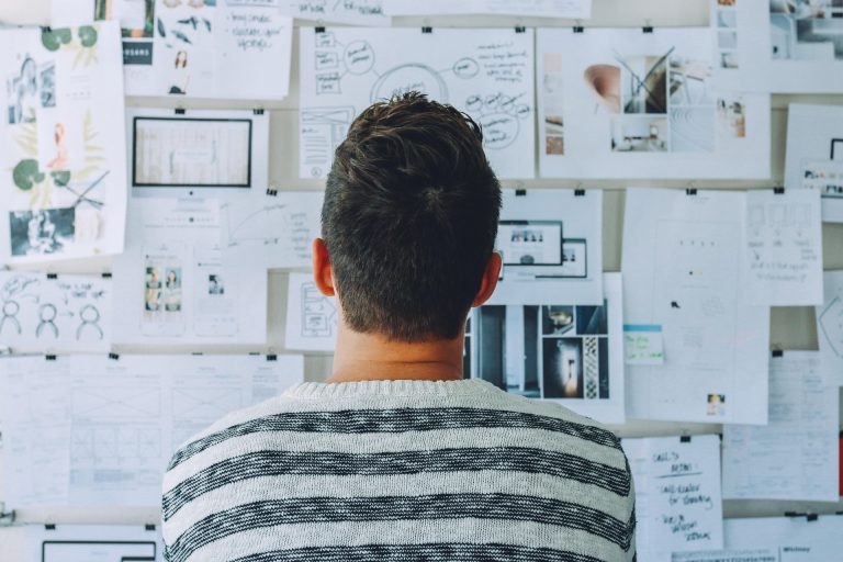 A man looking at a series of charts and data arranged on a board, making for data chaos.