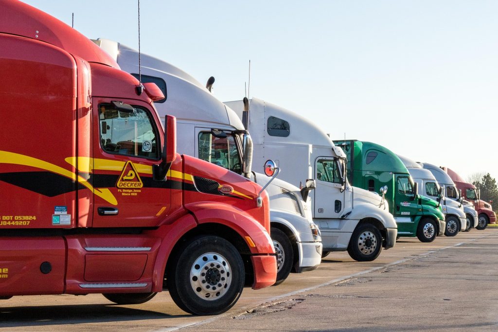 A fleet of truck vehicles for a business fleet, lined up in a parking lot.