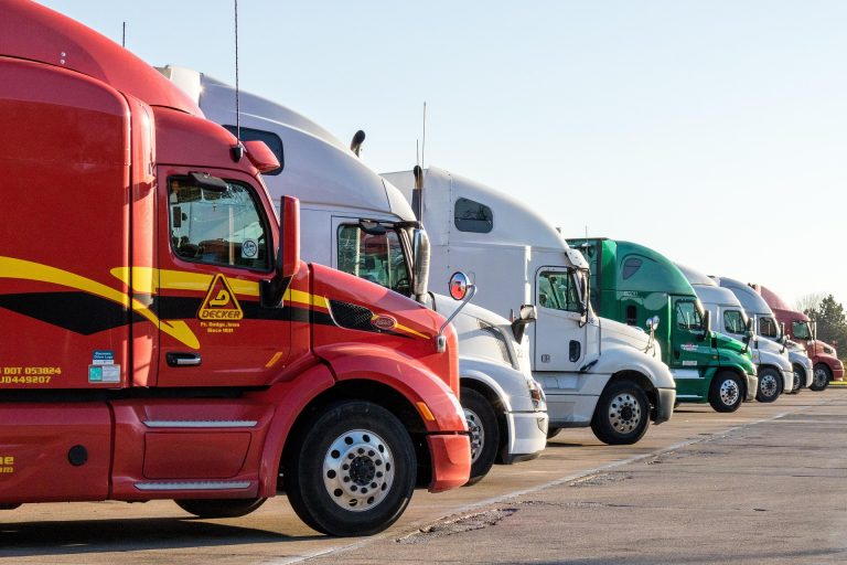 A fleet of truck vehicles for a business fleet, lined up in a parking lot.