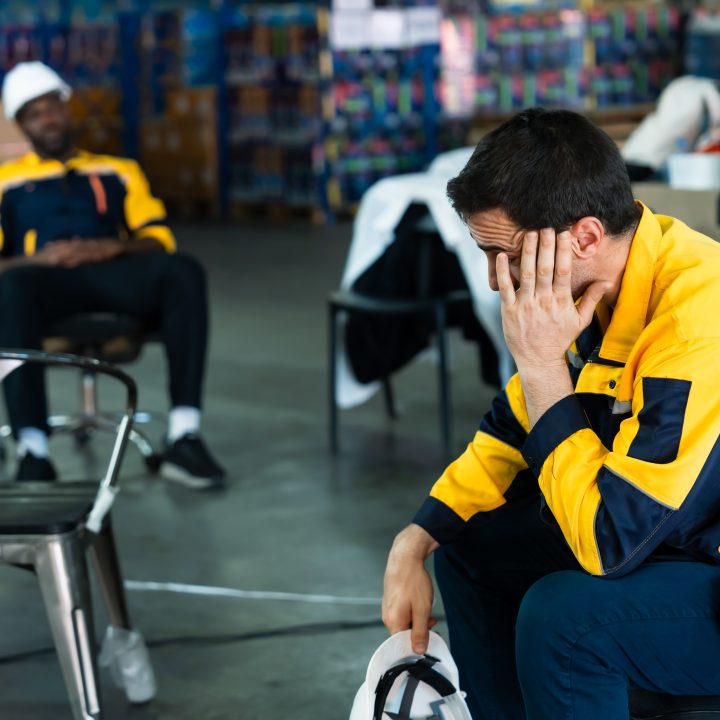 A frustrated warehouse worker sitting with his hand on his face, highlighting the negative impact of poor supply chain delay tracking.