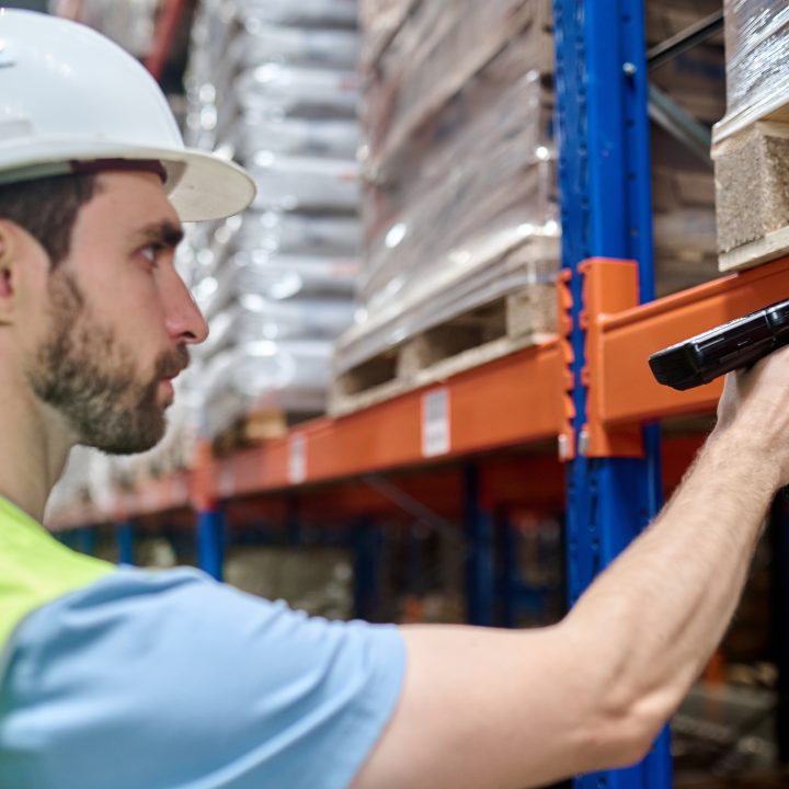 Warehouse worker scanning a lot number label on a storage rack for lot and serial tracking