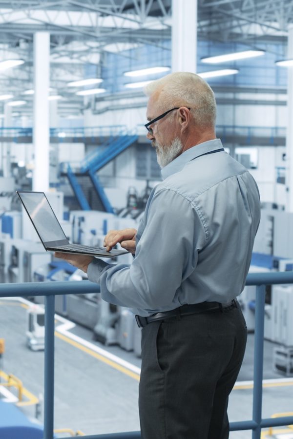 Senior,Factory,Manager,Working,On,Laptop,At,A,Futuristic,Industrial